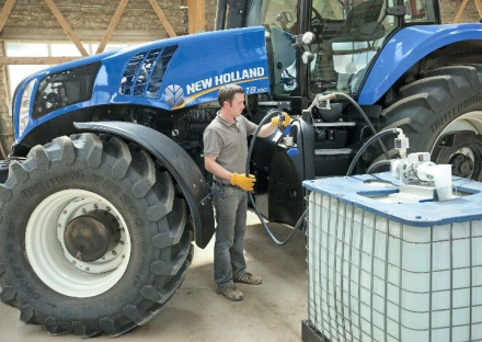 En mand fra Ole's olie fylder AdBlue på en blå traktor