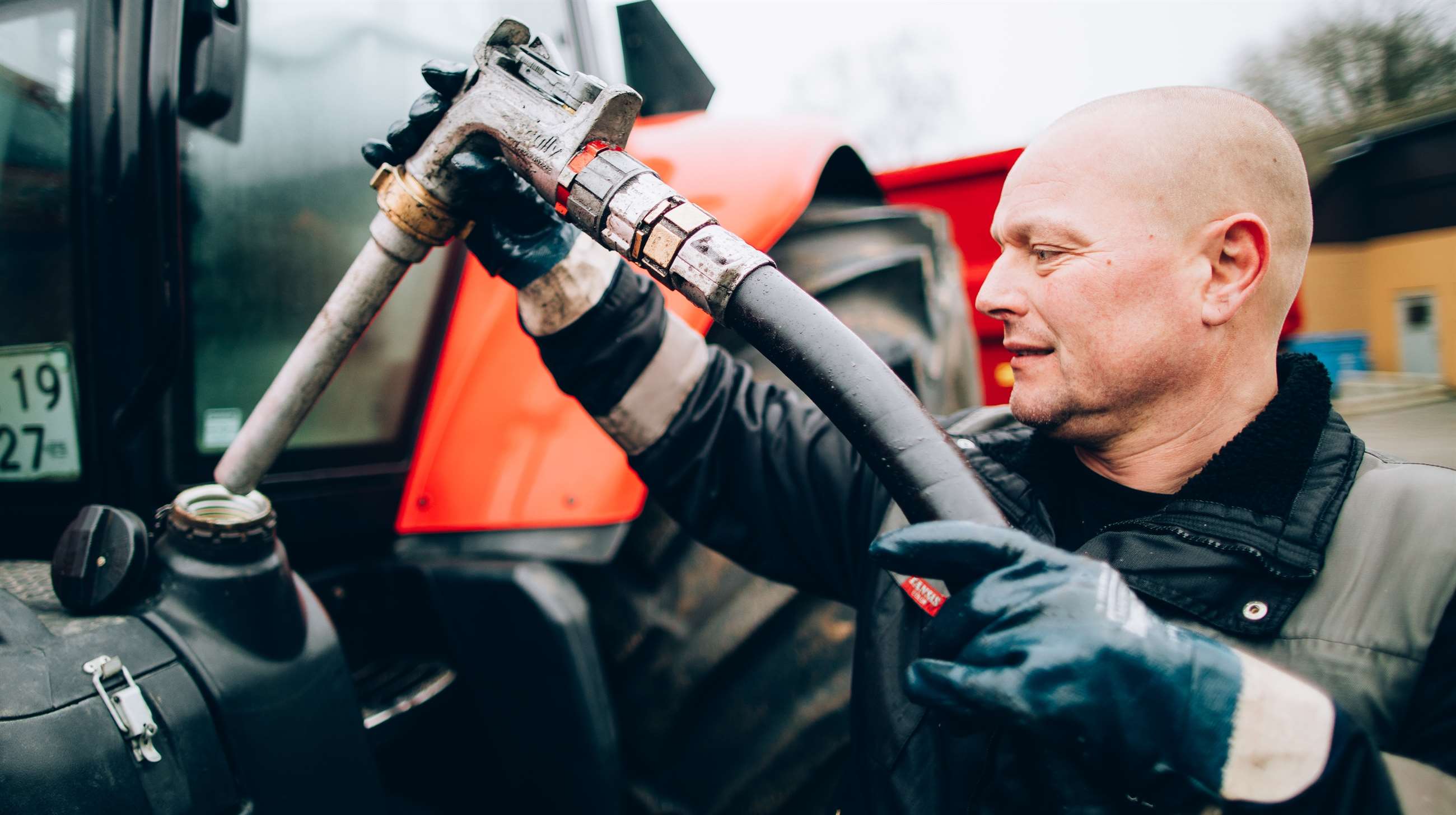 En mand fylder benzin på en traktor